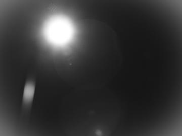 A black and white, blurry image of a streetlamp light at night