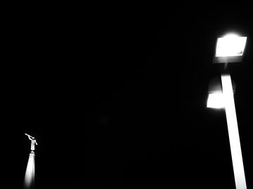 A stark, black and white photograp of streelights at night