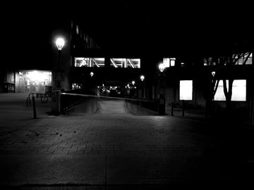 Black and white image of a building at night showing a warehouse door and ramp down to a parking garage