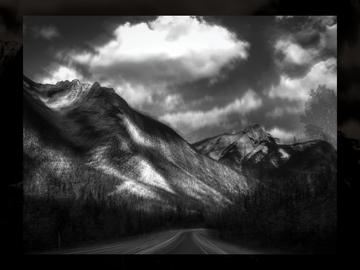 A picture in picture image of a black and white, blurry mountain highway. 