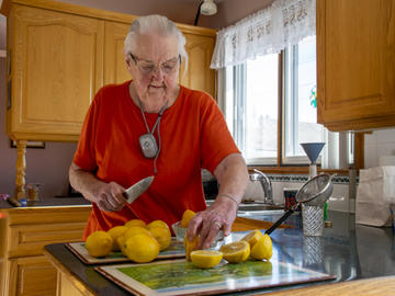 An elderly woman in the midst of chopping lemons