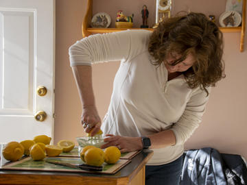 A middle-aged woman juices lemons in a kitchen