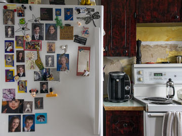 A kitchen with dark cherry wood cabinets. The fridge is covered in children's school portraits.