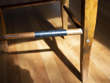 Photograph of wooden chair frame with black tape on it
