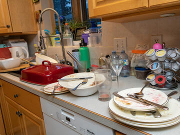 Dirty dishes are piled up on a kitchen sink and counter