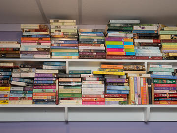 Two rows of shelves are packed with paperback books