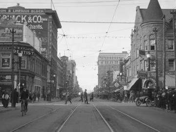Historical photo of 8th Avenue, Calgary c. 1920 showing street car tracks, man on bicycle, police officer standing at intersection