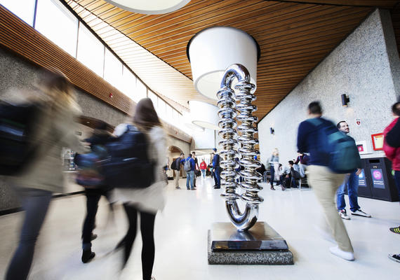 Katie Ohe's The Zipper sculpture is in the foreground in Science Theatres. Students walk on either side of it.