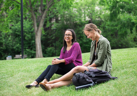 Two students sit on the lawn