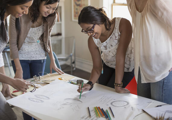 Women at a drafting table reviewing a document together. 