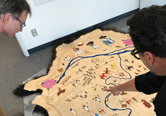George Colpitts and artist Adrian Stimson examine the First Nations Stampede Map created by Stimson.