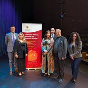 speakers and moderator standing around CMSS banner