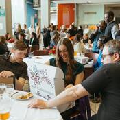 A recipient opens the indigenous box while some people watching