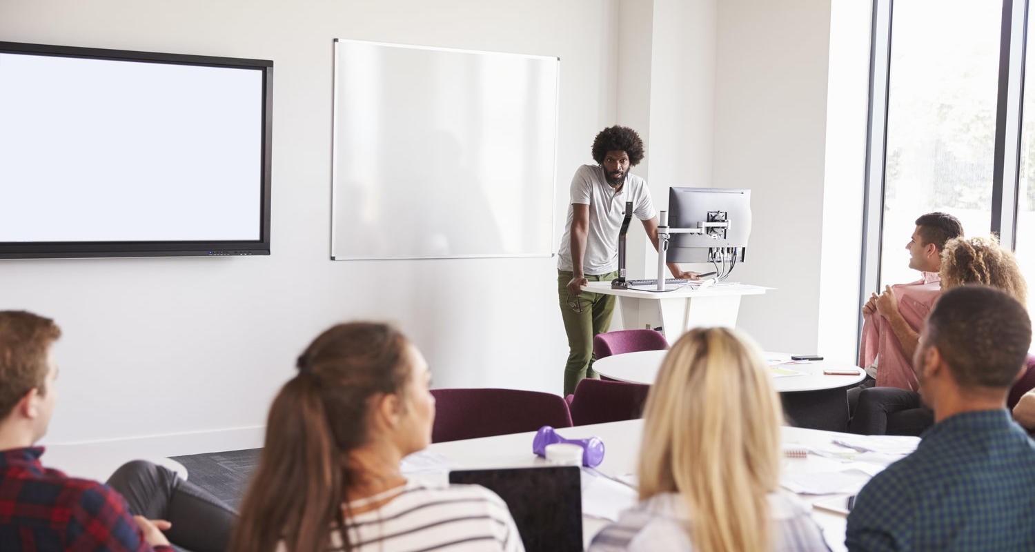 Stock image: a man chats at the front of a classroom to students