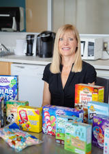 Charlene Elliott sits behind a row of colourful boxes of gluten-free food aimed at children