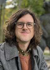 Portrait of Trevor Stark taken outdoors with trees and statue of bear in background
