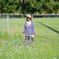 Maria Zytaruk stands beside a field of growing flax plants