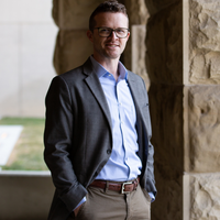 Jack Lucas wearing a suit with hands in pocket looking at the camera