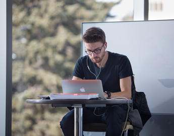 A male student studies on his laptop in the library