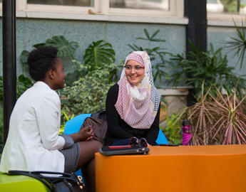 Two students chat in the administration building atrium