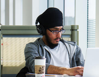 A student wearing a turban studies in the library