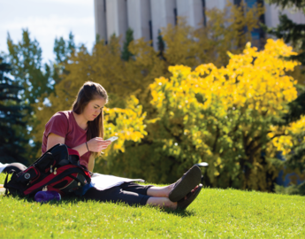 Student sitting in a field on campus