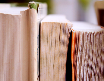 Close-up view of the top edges of aged hardcover books, highlighting their worn pages.