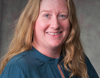 Dr. Roberta Rice with long hair wearing a blue top, face obscured by a blurred area.